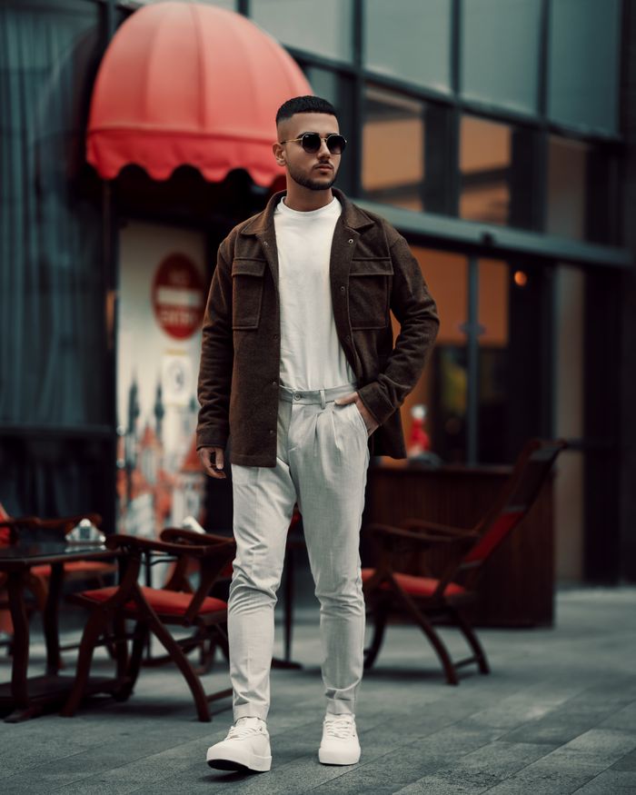 Fashionable young man in sunglasses walking through a vibrant cityscape in Tehran, Iran.