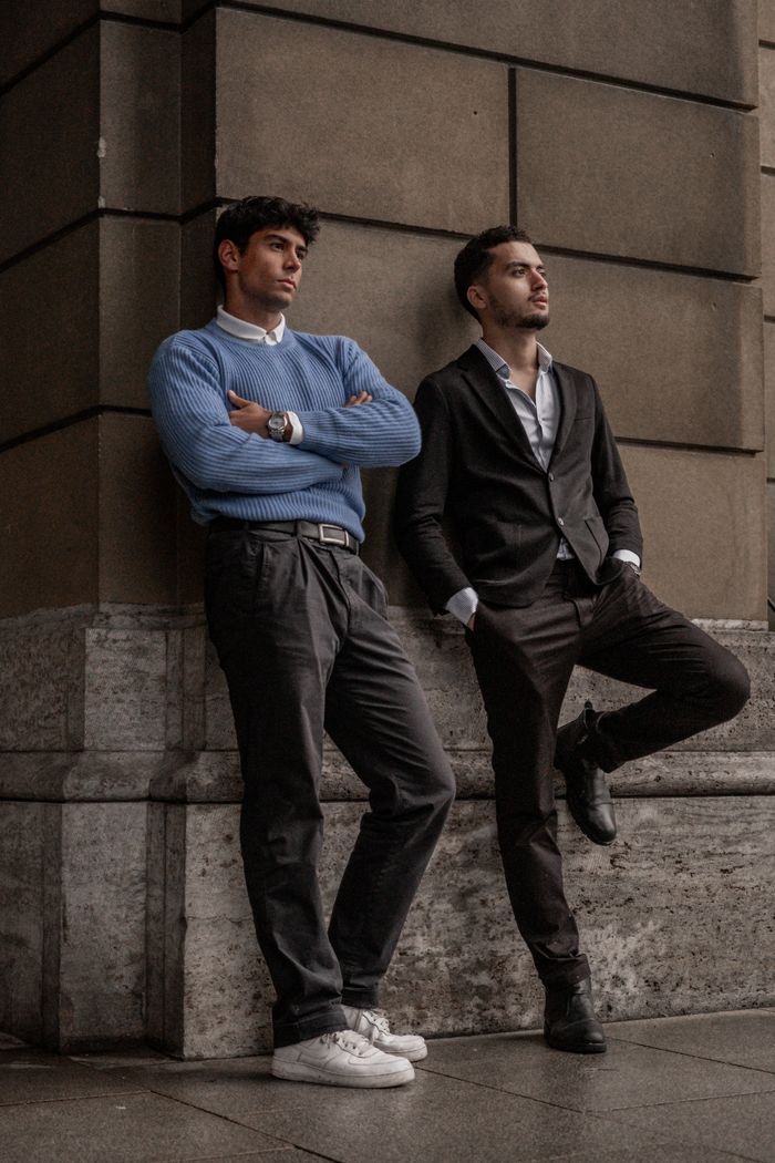Crafting Captivating Headlines: Your awesome post title goes here Two fashionable men pose against a building wall in an urban setting. Stylish and modern vibe.